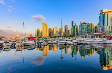 Sunset at Coal Harbour in Vancouver British Columbia with downtown buildings boats and reflections...