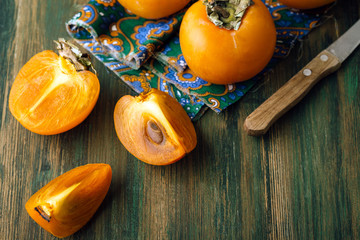 Persimmon, cut, green wooden old background
