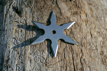 Shuriken (throwing star), traditional japanese ninja cold weapon stuck in wooden background