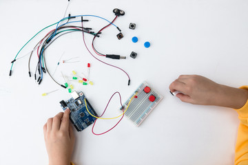A cute girl constructs robot arduino and program it. The boards and microcontrollers are on the table. STEM education. Programming. Mathematics. The science. Technologie. DIY. 