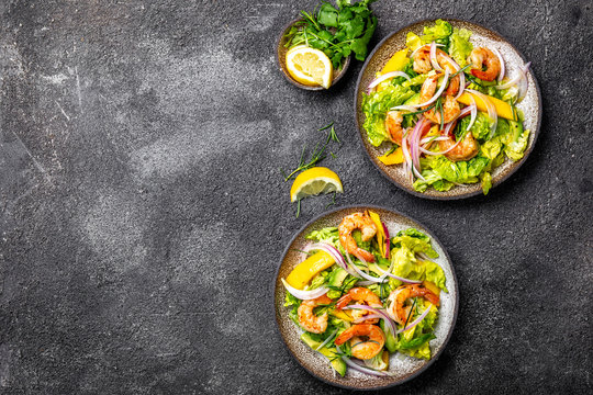 Fresh Shrimps, Mango Avocado lettuce salad, olive oil and lemon dressing. healthy food. Top view, gray background