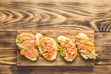 Bruschetta with sliced fish salmon, cucumber, arugula and young grass sprouts
