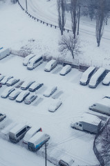 Cars covered with snow in the parking lot during a snowfall