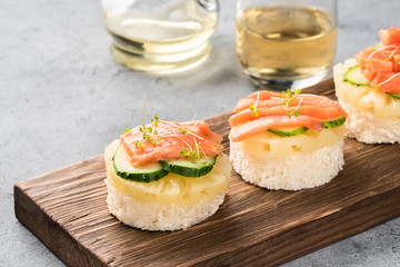 Bruschetta toast of white bread with slices of pineapple cucumber fish salmon fresh green sprouts