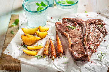 Homemade tbone steak served with water on white table