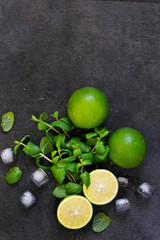 Fresh mint, lime and ice on a black background. Ingredient for mahito. Top view