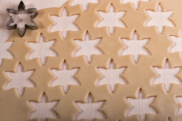 Obraz premium Raw dough for Christmas cookies for children, making gingerbread cookies in the shape of snowflakes close-up. Cutting the shape. Home bakeries