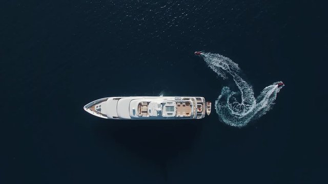 Aerial view of two jet-ski near the large yacht