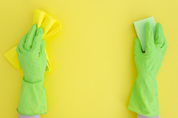 two Hands in green cleaning rubber glove with sponge isolated on yellow background.