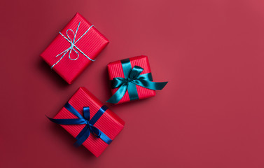 Christmas gift boxes wrapped in red paper on red background. Bright and festive Christmas concept. Top view, flat lay. Copy spce for text.