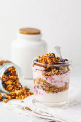 Baked granola, jam and yogurt healthy breakfast parfait in glass.