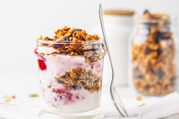 Baked granola, jam and yogurt healthy breakfast parfait in glass. - obrazy, fototapety, plakaty