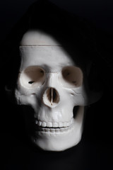 Human skull in hood on dark