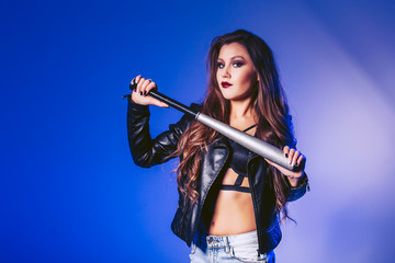 A beautiful girl is holding a baseball bat. Shooting in the studio