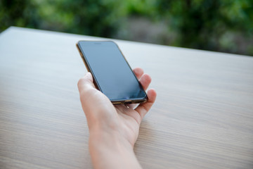 Closeup of female hands holding smart phone on outdoors background. Top side overhead view of mockup display nature backdrop, modern digital device mobil communication technology connection.