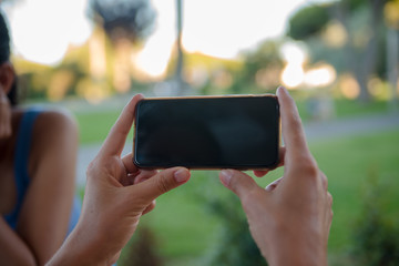 Closeup of female hands holding smart phone on outdoors background. Top side overhead view of mockup display nature backdrop, modern digital device mobil communication technology connection.
