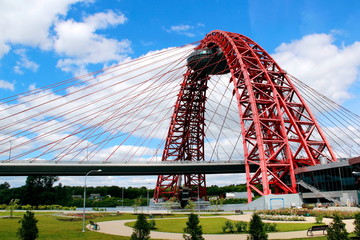 red metal arch over the bridge against the blue sky with white clouds - Powered by Adobe