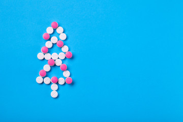 Conceptual background on the medical theme for the new year and Christmas, a Christmas tree of white pills decorated with red pills top view with space for text.