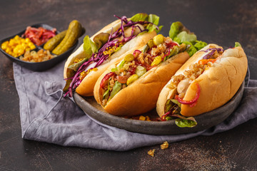 Hot dogs with assorted toppings on a dark background, top view, copy space.