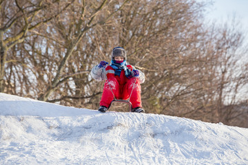 boy at the sledge on top of snowy hill waiting for riding