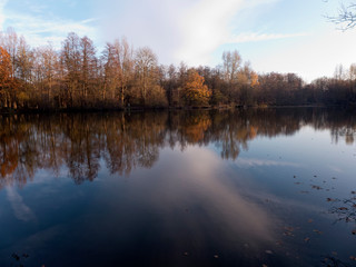 Spaziergang im Herbst entlang eines kleinen Sees in Bünde Deutschland. Wunderschöne Spiegelungen der Bäume im Wasser.
