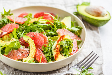Avocado and grapefruit salad in a white plate on a white background.