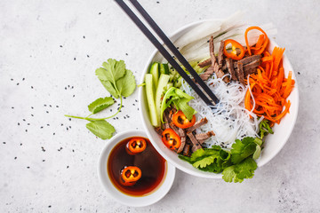 Bun cha salad bowl. Vietnamese rice noodle with beef and chilli vegetables salad in white bowl,...