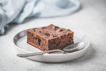 Piece of chocolate vegan cake with chocolate drops and nuts.