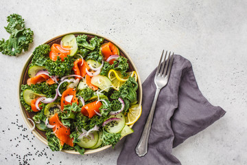 Salted salmon (trout) and Kale salad in a white plate on a white background, top view.