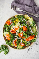 Salted salmon (trout) and Kale salad in a white plate on a white background, top view.