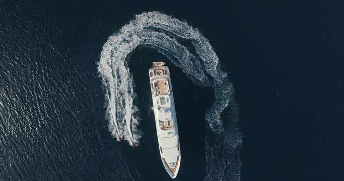 Aerial view of two jet-ski moving around large yacht