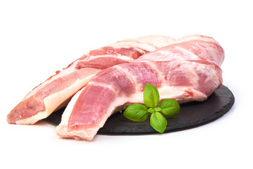 Fresh Raw Pork Tenderloin on a slate shale plate with basil leaves, isolated on a white background. Close-up
