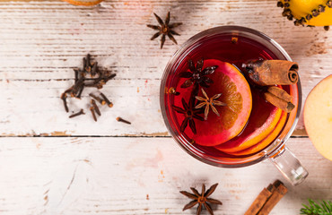 Christmas hot mulled wine with spices on wooden background.