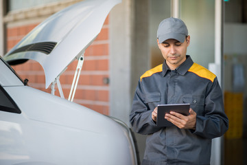 Mechainc using a tablet in front of a van