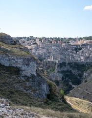 Fototapeta na wymiar Houses built into the rock in the cave city of Matera, Basilicata Italy. Matera has been designated European Capital of Culture for 2019. Photographed from inside a cave in the ravine opposite.