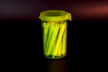A bright transparent green RX pill bottle filled with marijuana joints.