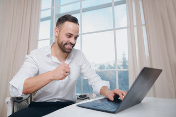 Smiling businessman with coffee in hand, use laptop on window background