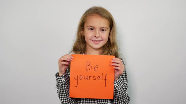 Sweet girl with inspirational slogan in hands. Be yourself 