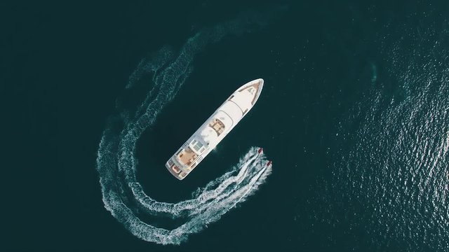 Aerial view of two jet-ski moving around large yacht