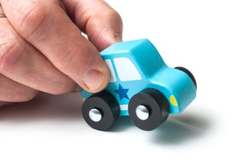 closeup of blue miniature wooden car in hand on white background - concept police