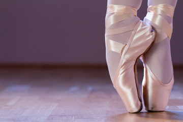 Feet dressing a pair of pointe shoes - obrazy, fototapety, plakaty
