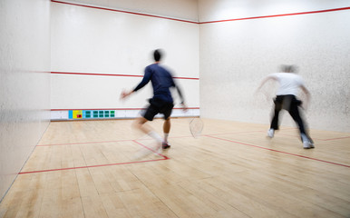 Fototapeta na wymiar Squash players in action on a squash court (motion blurred image; color toned image)