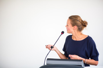 Pretty, young business woman giving a presentation in a conference/meeting setting (shallow DOF;...