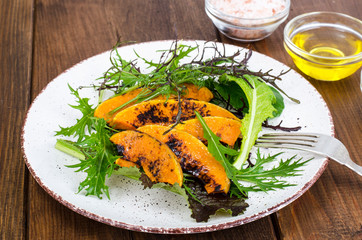 Healthy and dietary food. Mix of lettuce leaves and baked pumpkin