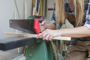 close up of a woman sawing wooden slat