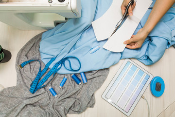 Sewing workshop. Seamstress at work. Marking and cutting fabric.