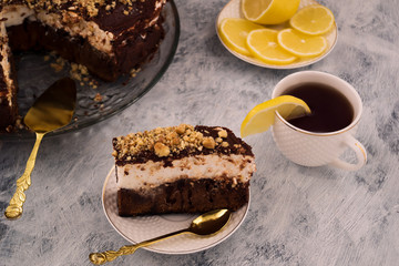 Sliced chocolate cake. Tea with lemon. Sliced lemon. Wooden background.