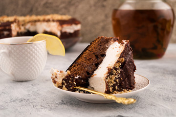 Piece of chocolate cake on a plate. Eating dessert. A slice of lemon on the edge of the Cup. Pitcher of herbal tea.