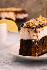 A sliced piece of chocolate cake. Layer of white cream. Crushed walnut. Vertical. Light background.