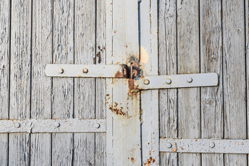Old wooden gate with peeling paint and loops for a padlock rusted closeup